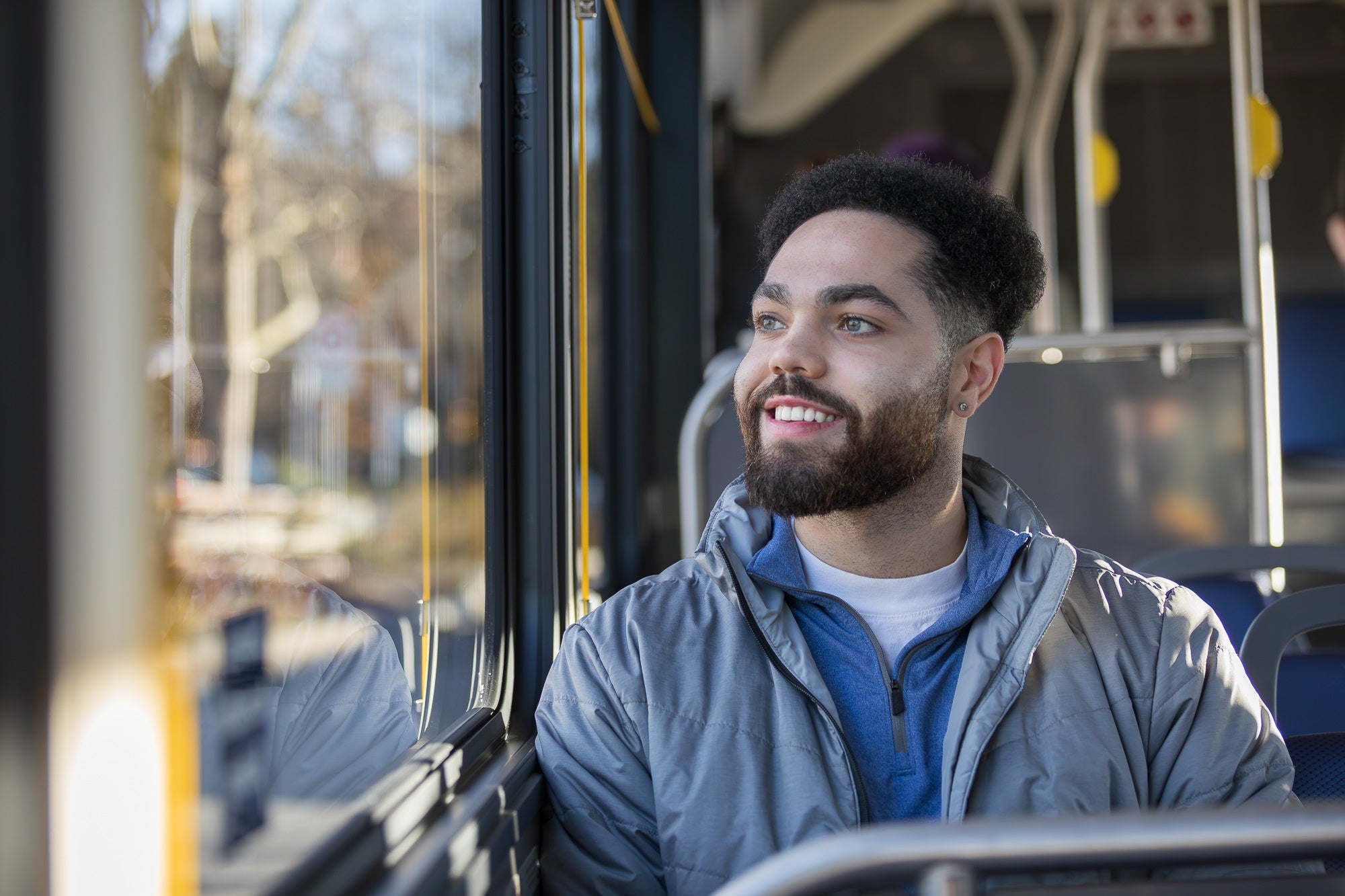 A young man on a bus, looking out the window.
