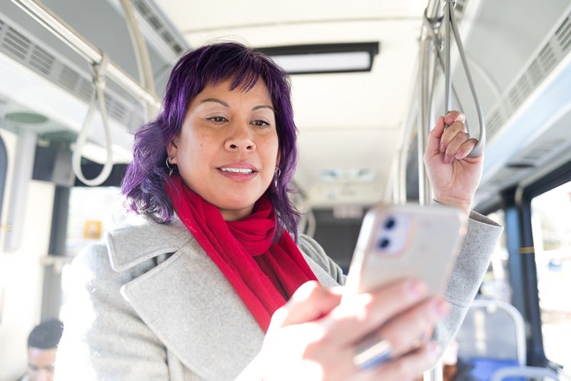 A woman is checking her phone on a bus.