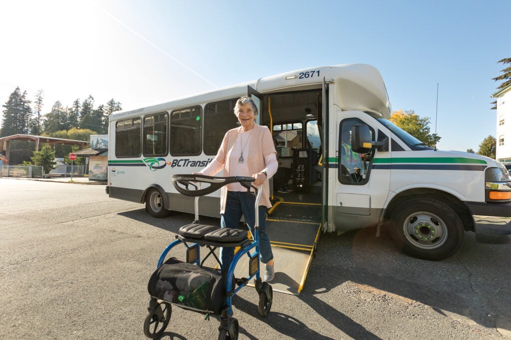 handyDART bus with ramp deployed. A user with a walker getting off the bus.