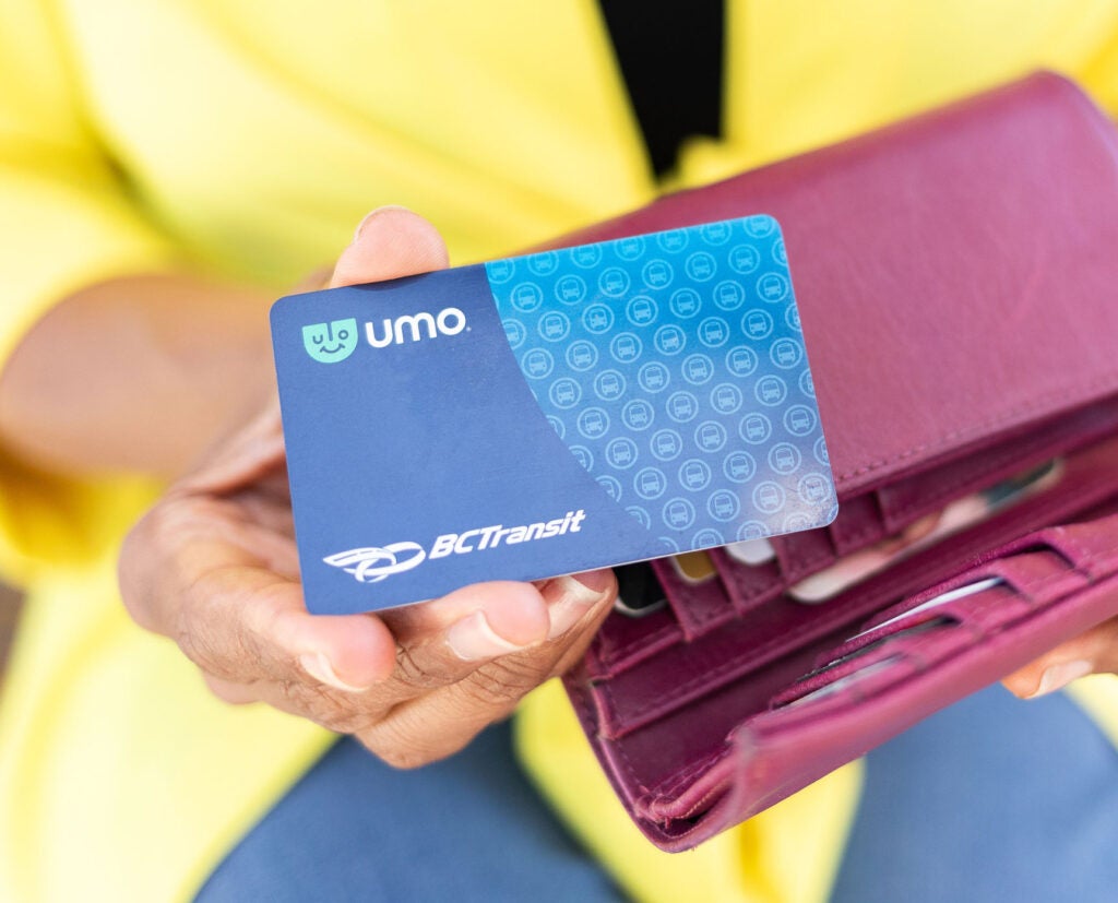 A close up of Umo fare card being held above a wallet.