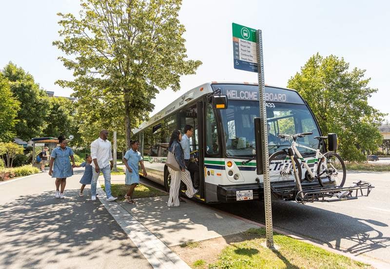 Many riders of all ages and backgrounds are queuing to board a transit bus.