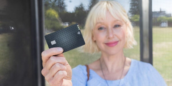 Woman holding credit card so she can pay for transit by tapping her card
