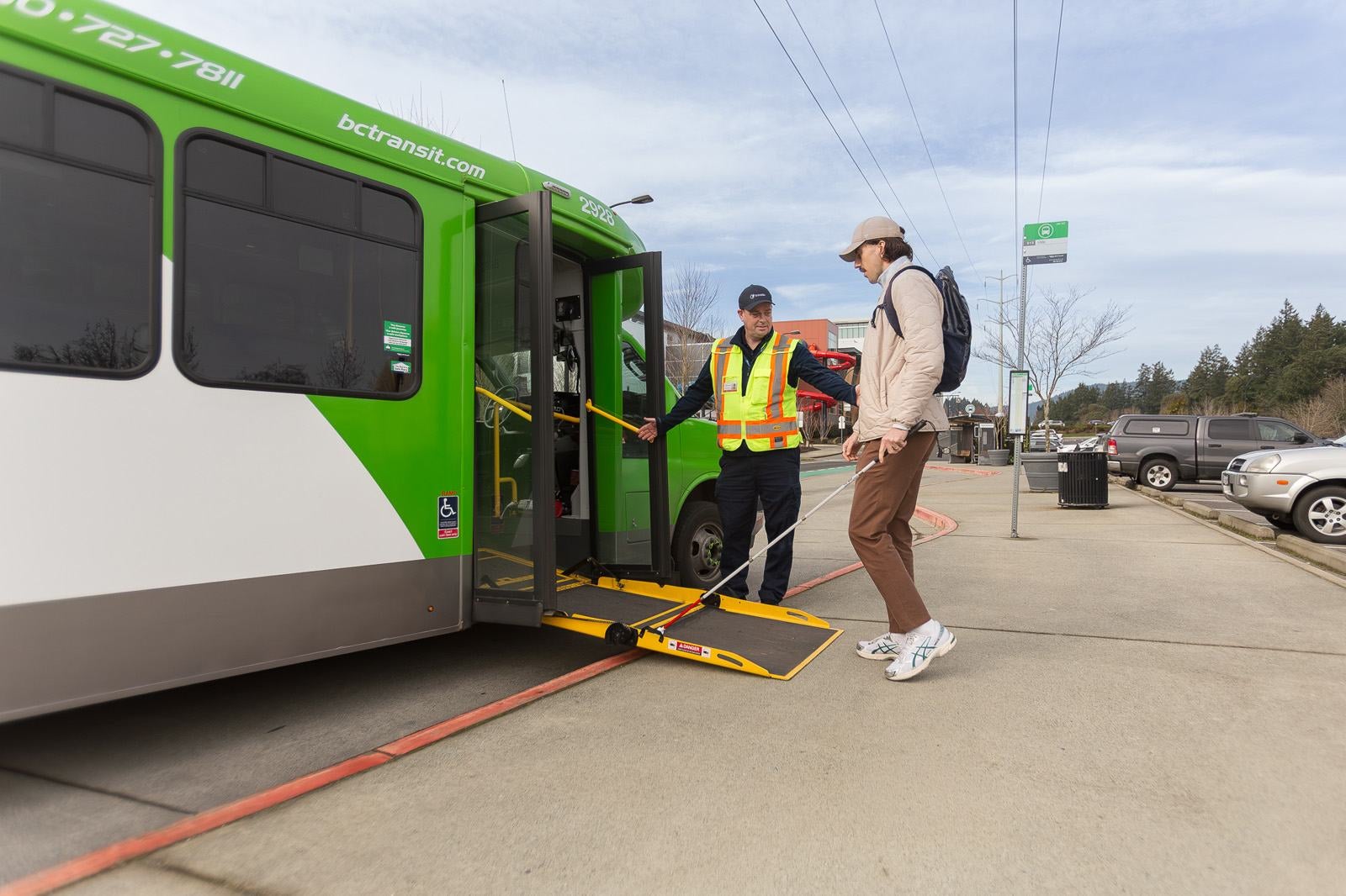 handyDART driver aiding a visually impaired passenger onto a bus.