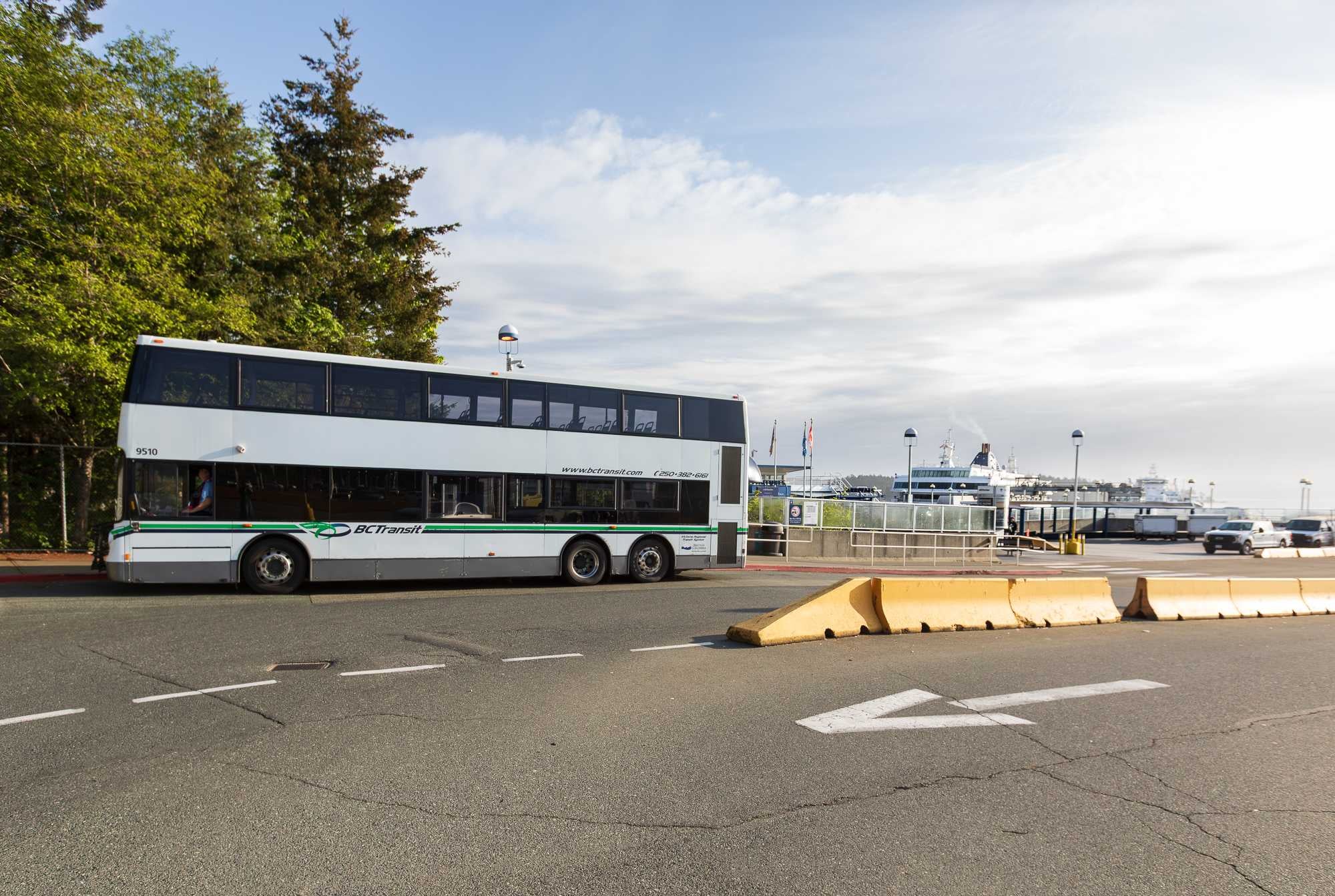 A double decker bus in front of a ferry terminal.