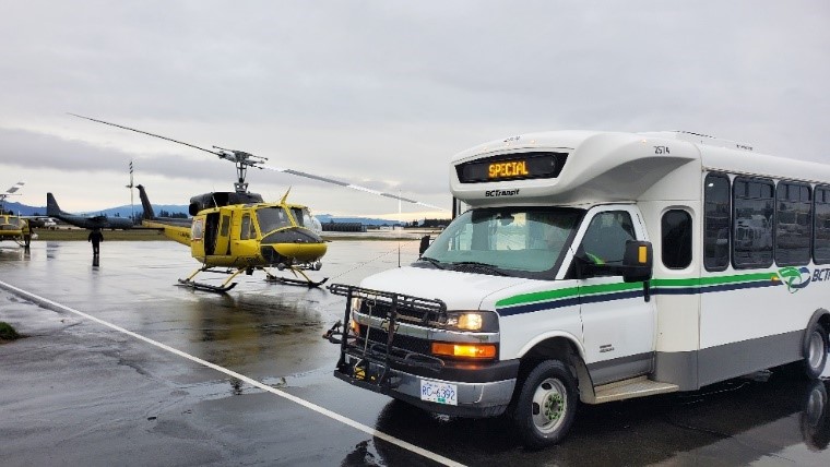 A HandyDART bus in front of a yellow Helicopter